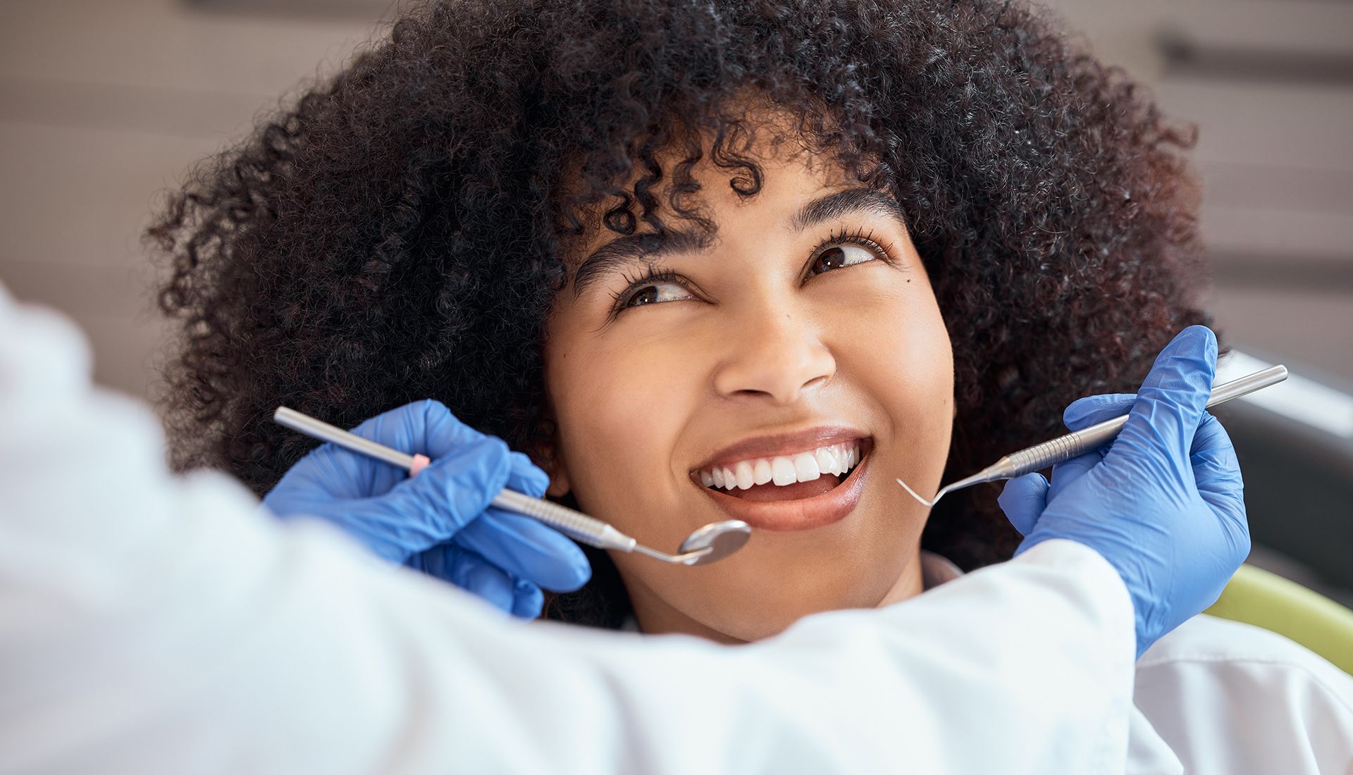 Chica afroamericana con un afro mirando al dentista en su cita dental. Tener su chequeo para prevenir caries y enfermedades de las encías.